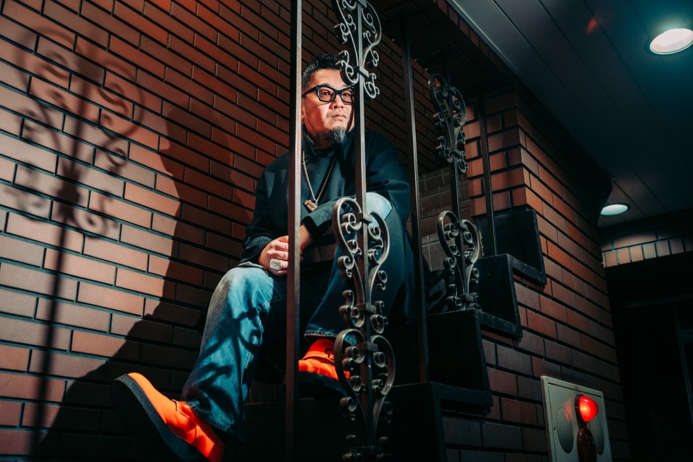 Shintaro Yamamoto sitting on brick steps in orange shoes